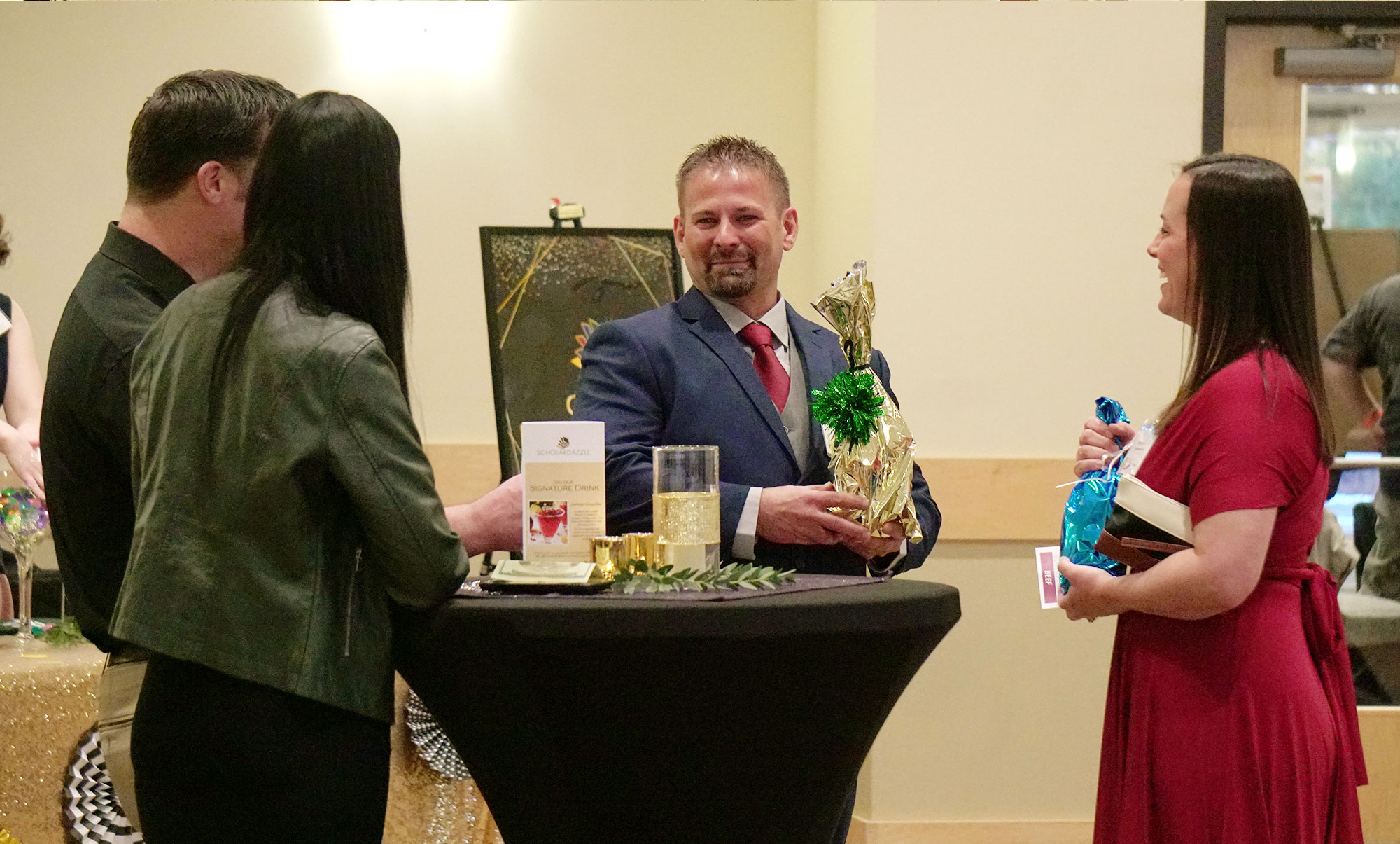 Four People Standing Around Table Smiling