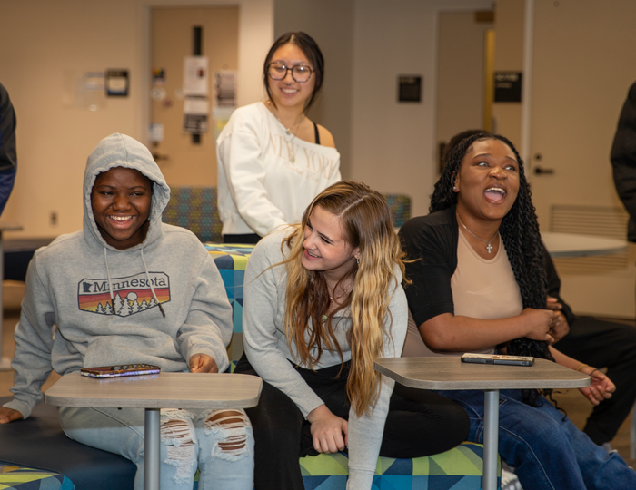 Four diverse female students in classroom laughing