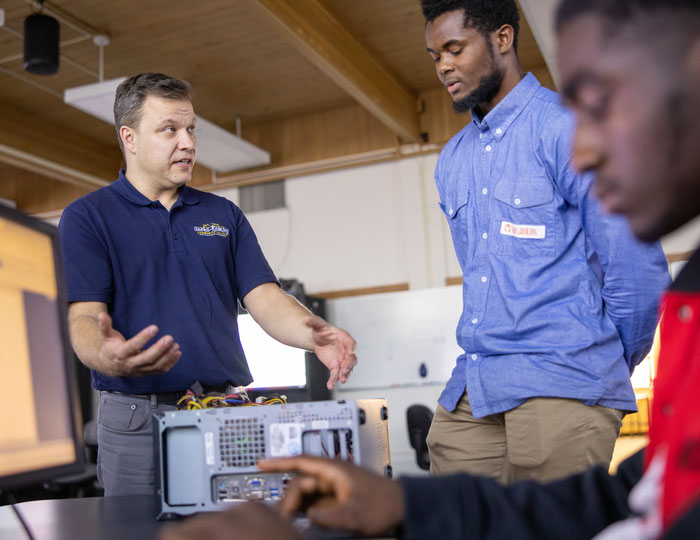 Instructor explaining computer networking concepts to students in a small classroom