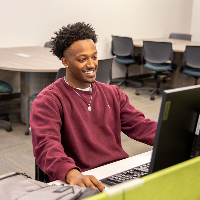 Computer science student working at a desktop computer in a campus lab