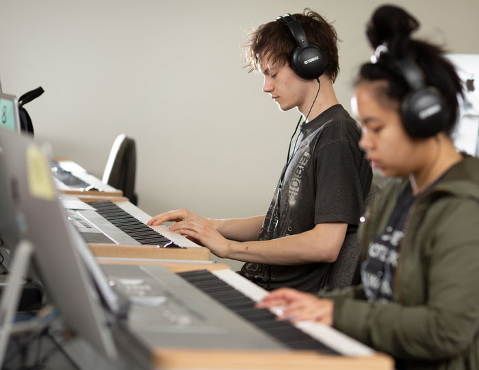 Students practicing piano skills, production on digital keyboards in a music lab.