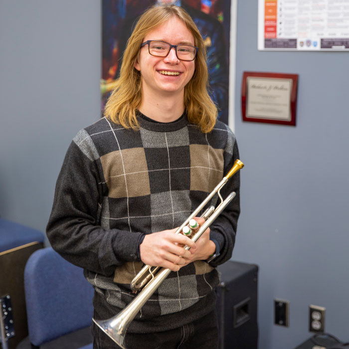 Student holding a trumpet in music classroom.