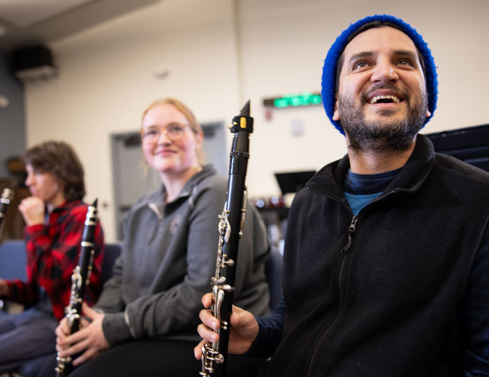 Students holding clarinets during a music rehearsal in a campus classroom.