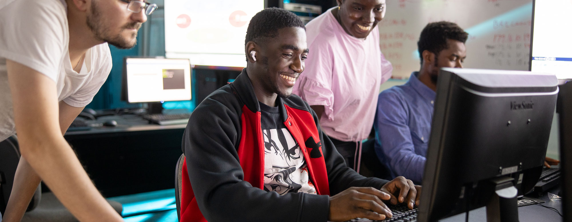 students collaborating at a computer workstation in a classroom