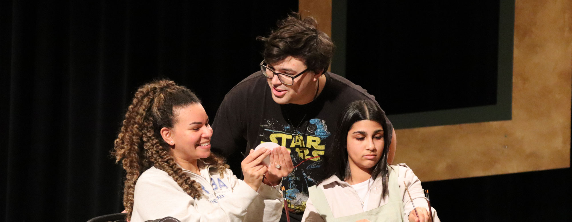 Students collaborating during a theater rehearsal on stage.