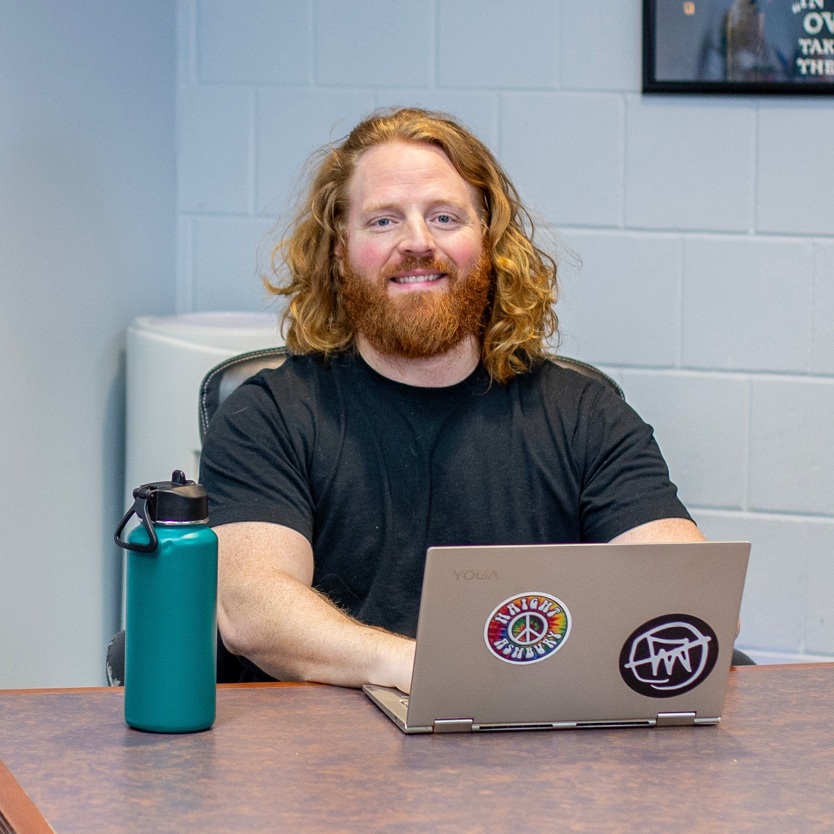 student smiling with laptop and water bottle at table