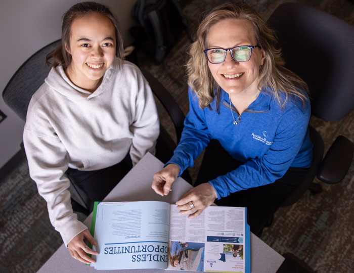 Overhead view of two people seated at a table reviewing a college brochure titled ‘Endless Opportunities’ at Anoka-Ramsey Community College