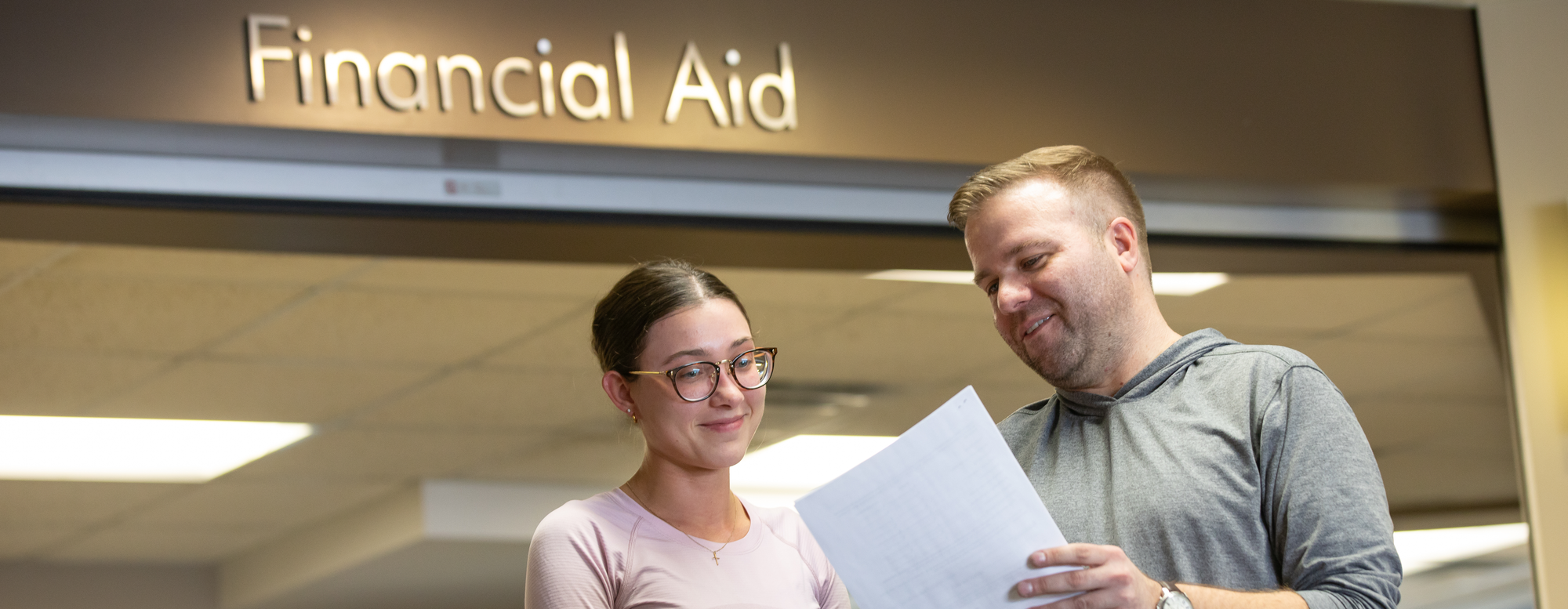 female student talking to male staff in front of financial aid office