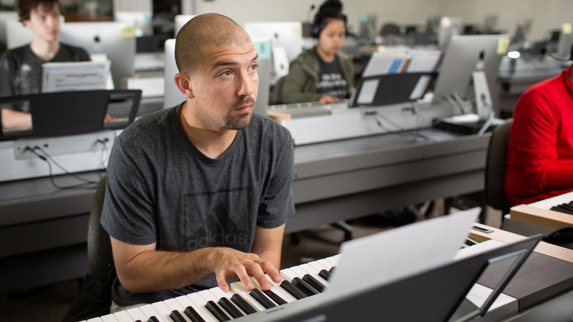 Student plays electronic keyboard in a music classroom with other students