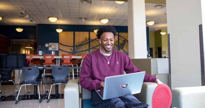 Coon Rapids Campus Riverside Cafe with male student sitting using a laptop.