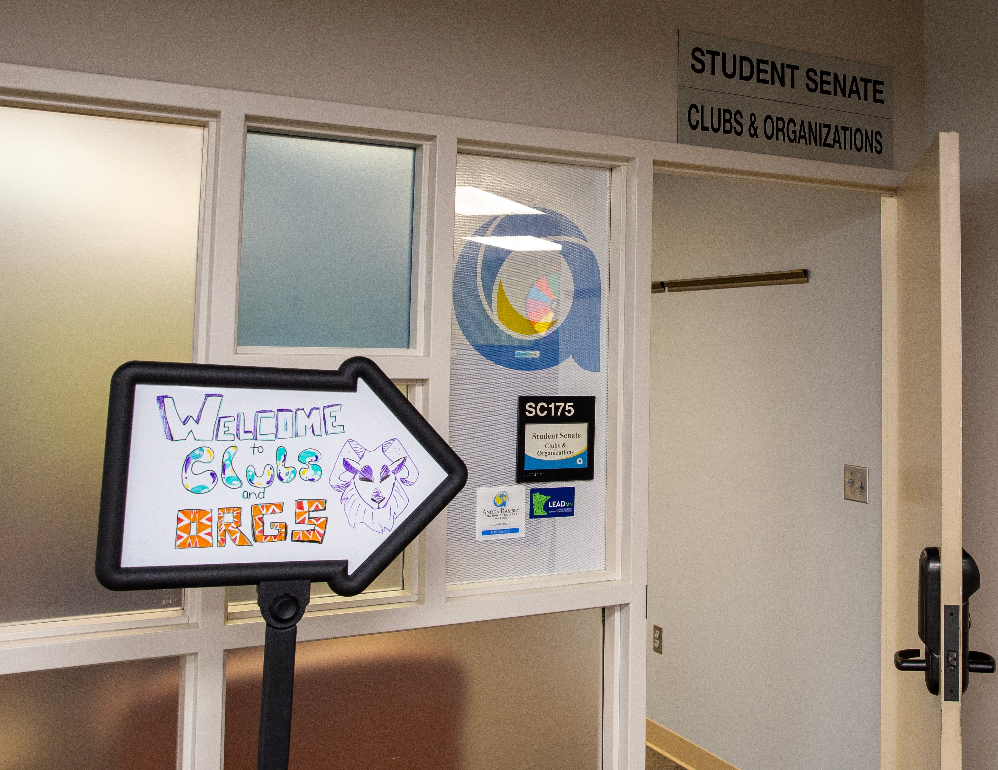 A sign that says "Welcome to Clubs and Orgs" pointing to an office for student senate and clubs and organizations