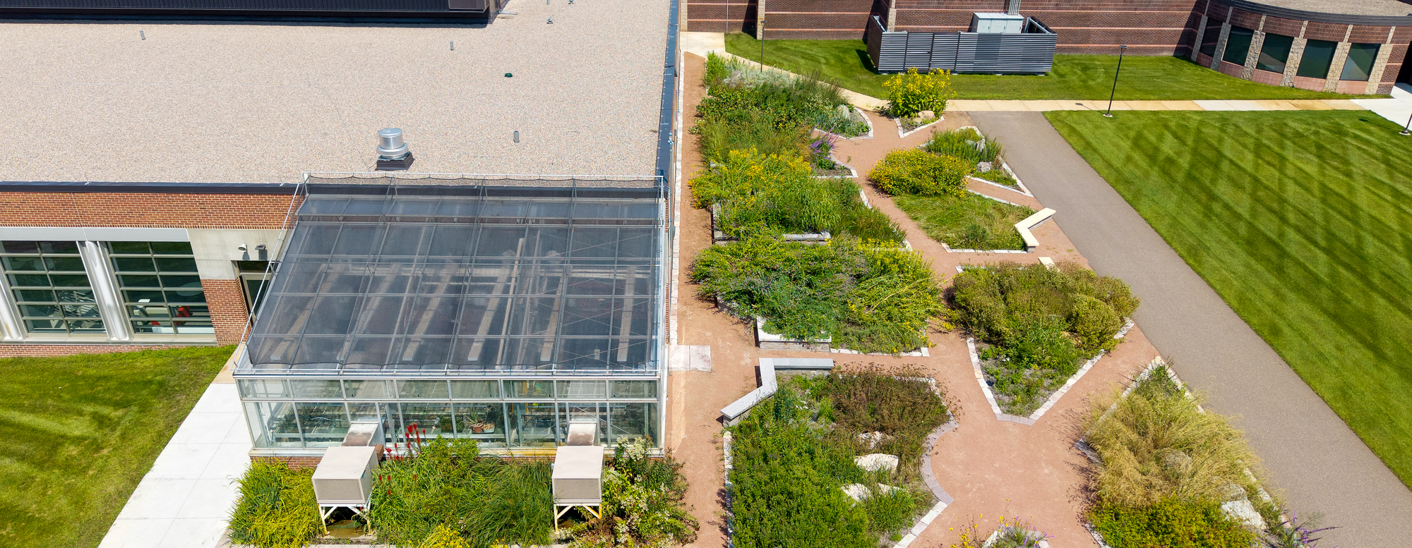 Aerial, outdoor view of the Science building's greenhouse and wildflower garden space.