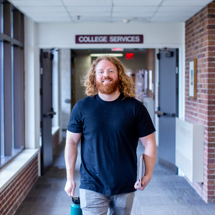 Smiling, male student walking in Technology Building hallway on Coon Rapids Campus