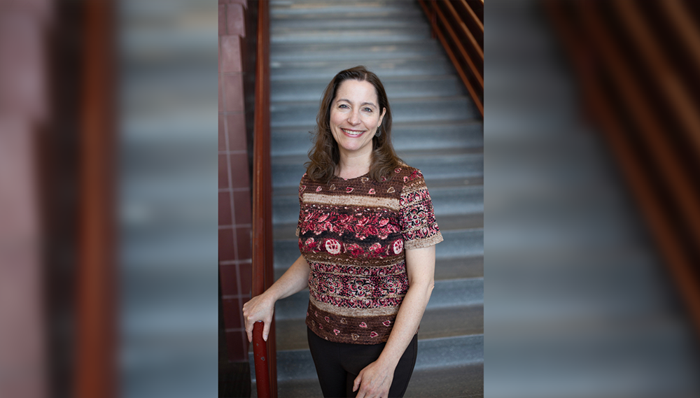 Individual standing at base of staircase, smiling directly at camera