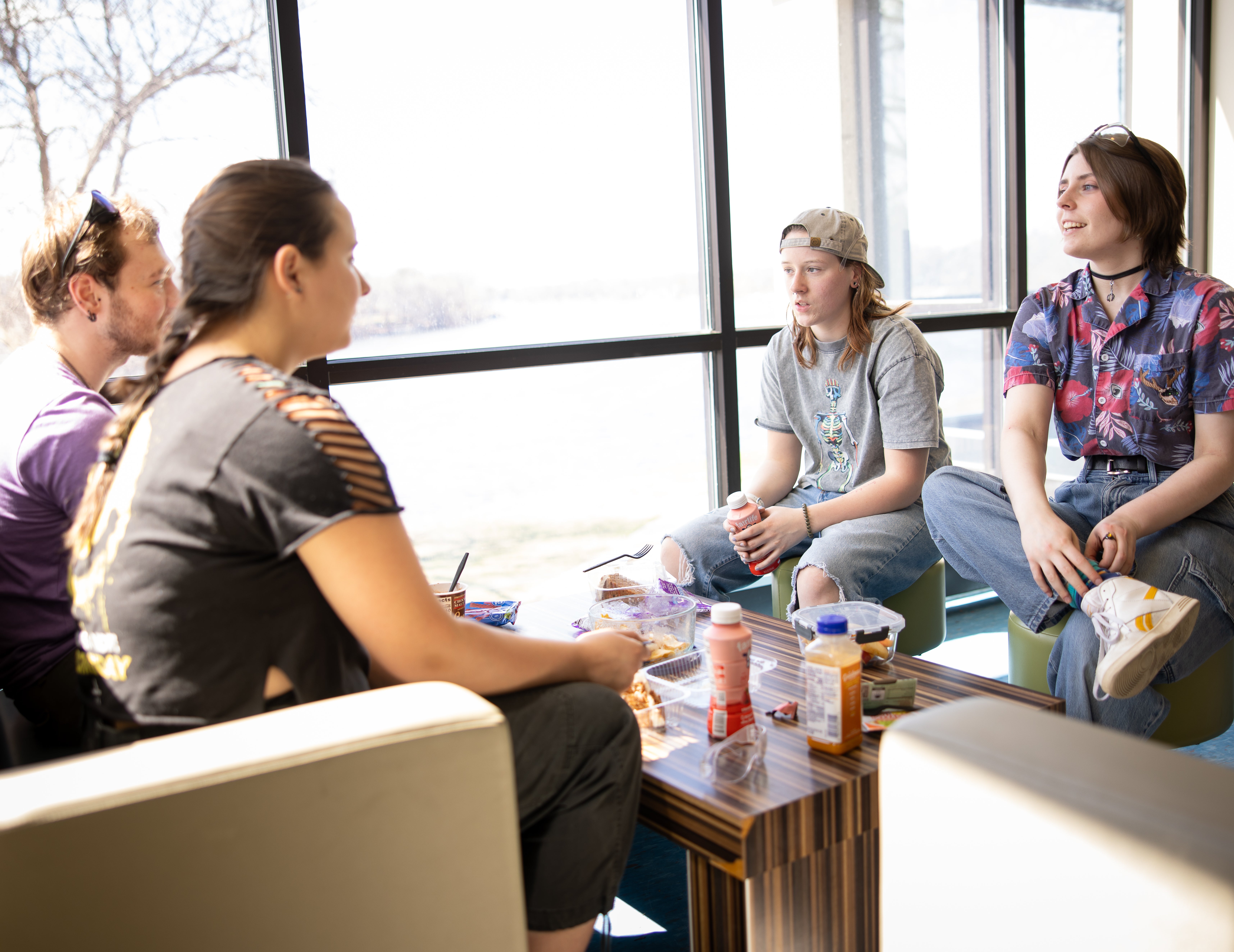 Group of four students facing one another talking smiling in casual space