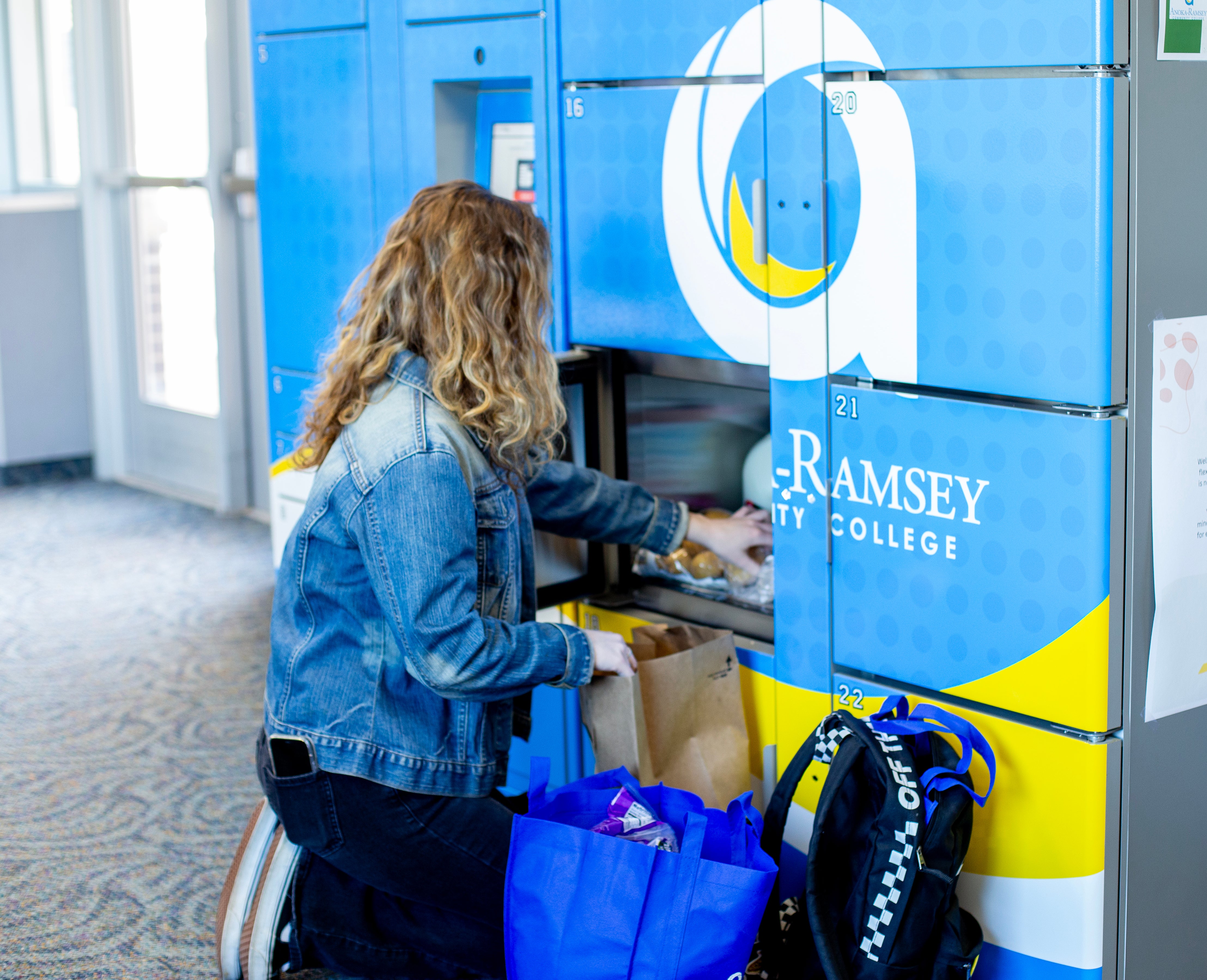 Individual kneeling in front of locker with bags of food nearby