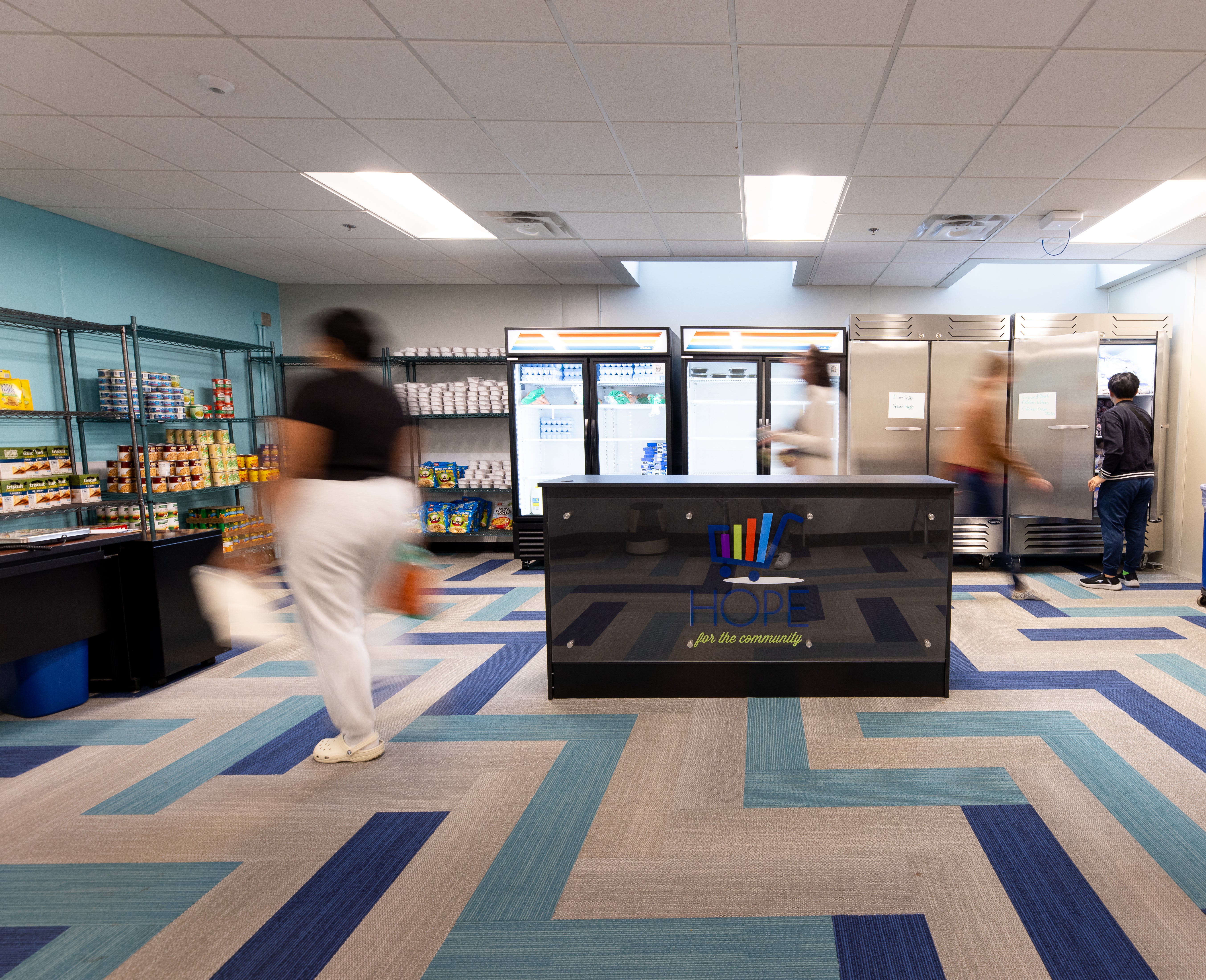 Interior of on-campus food pantry. Blurred individuals appear to be moving around space.