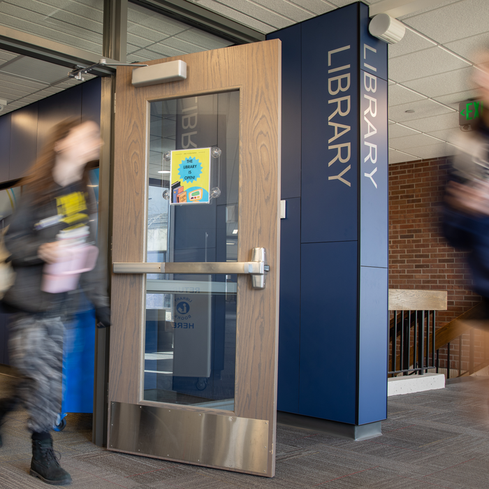 Individual exiting door near signage reading "Library"